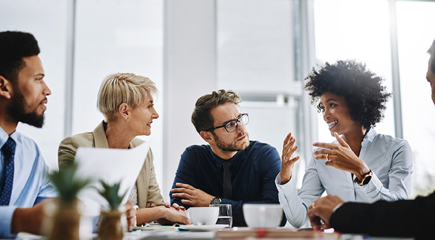 Four people sit at a table discussing business.