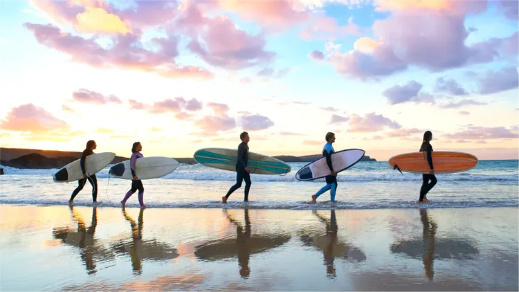 Surfers walking along the beach with surfboards